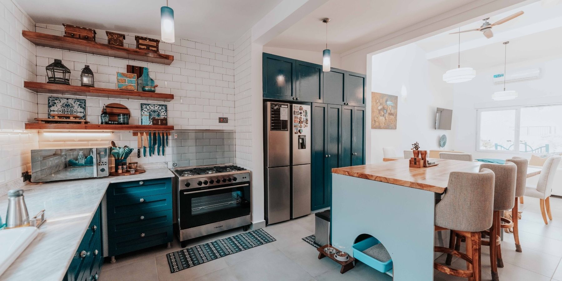 Open-plan kitchen with dark fitted cabinets, wooden island worktop, range cooker and open shelving