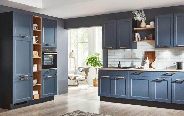 Modern fitted kitchen with dark blue cabinetry, integrated oven, open shelving and white tiled splashback