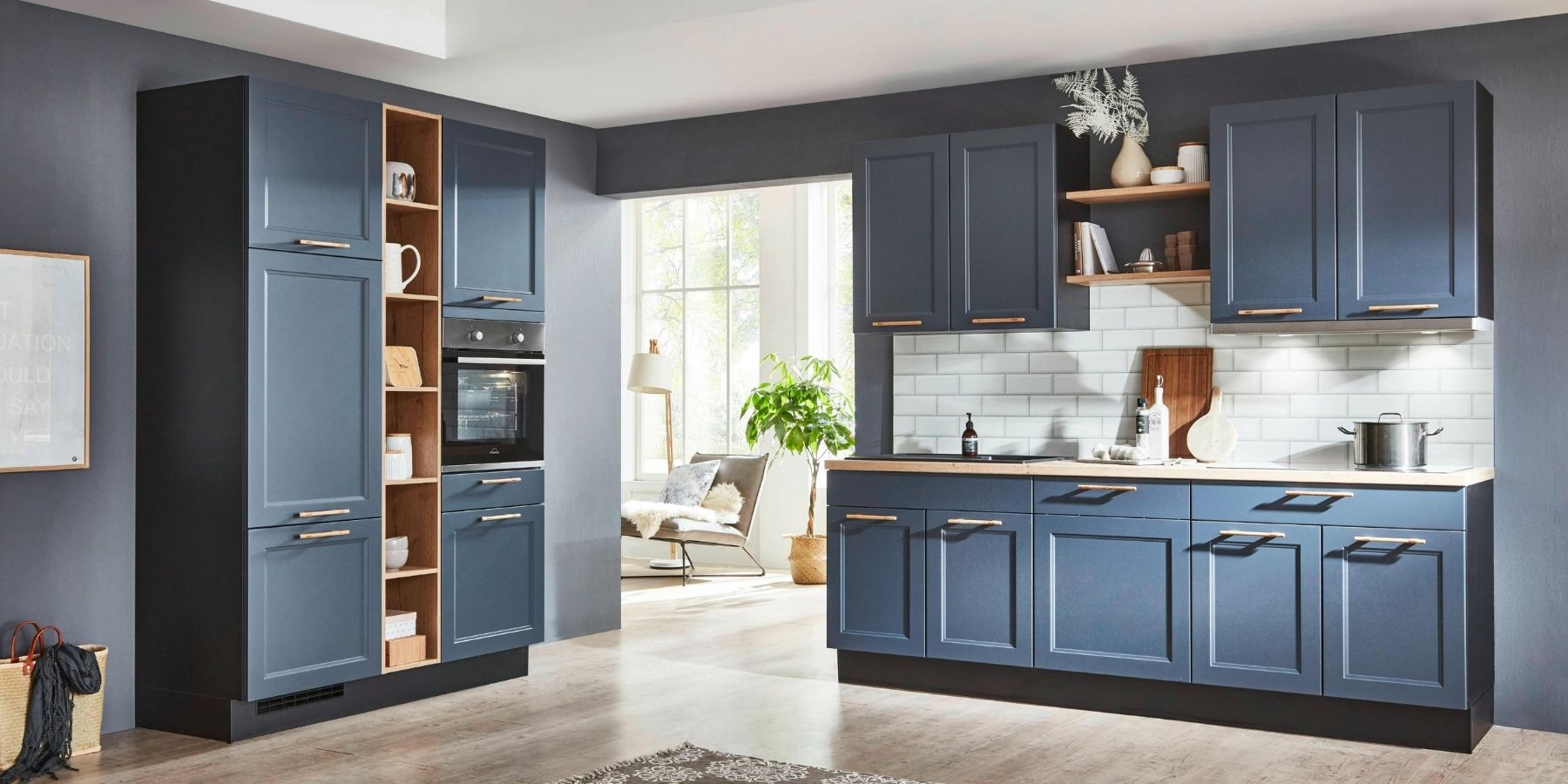 Modern fitted kitchen with dark blue cabinetry, integrated oven, open shelving and white tiled splashback