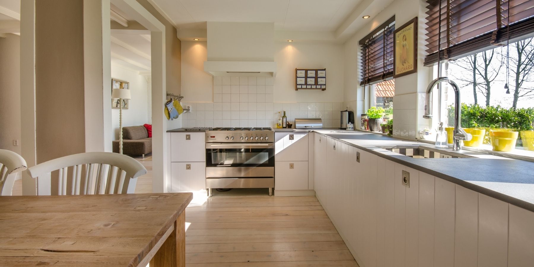 Bright fitted kitchen with light cabinetry, dark worktops, range cooker and large windows