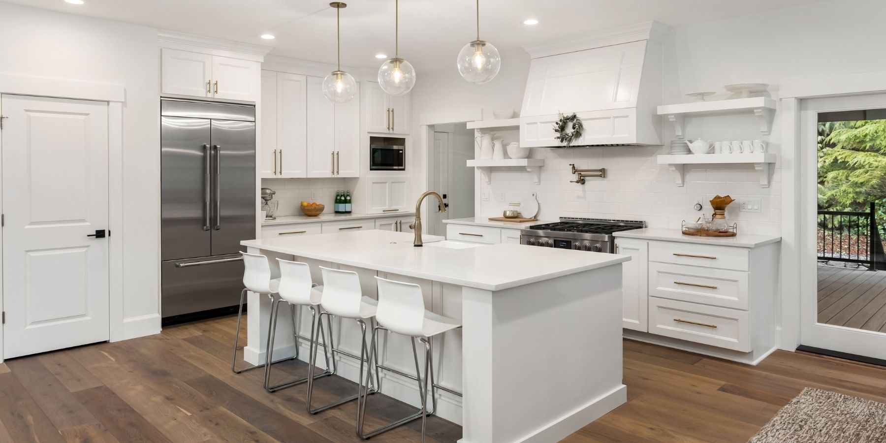 Bright white fitted kitchen with central island, integrated appliances, pendant lighting and timber flooring