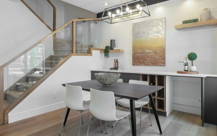 Modern dining area with glass-balustrade staircase, built-in storage and contemporary lighting