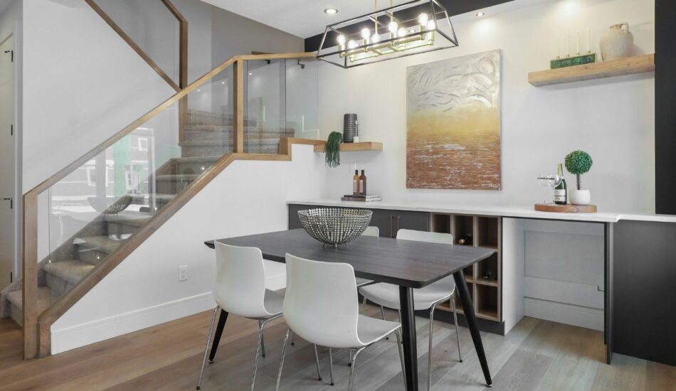 Modern dining area with glass-balustrade staircase, built-in storage and contemporary lighting