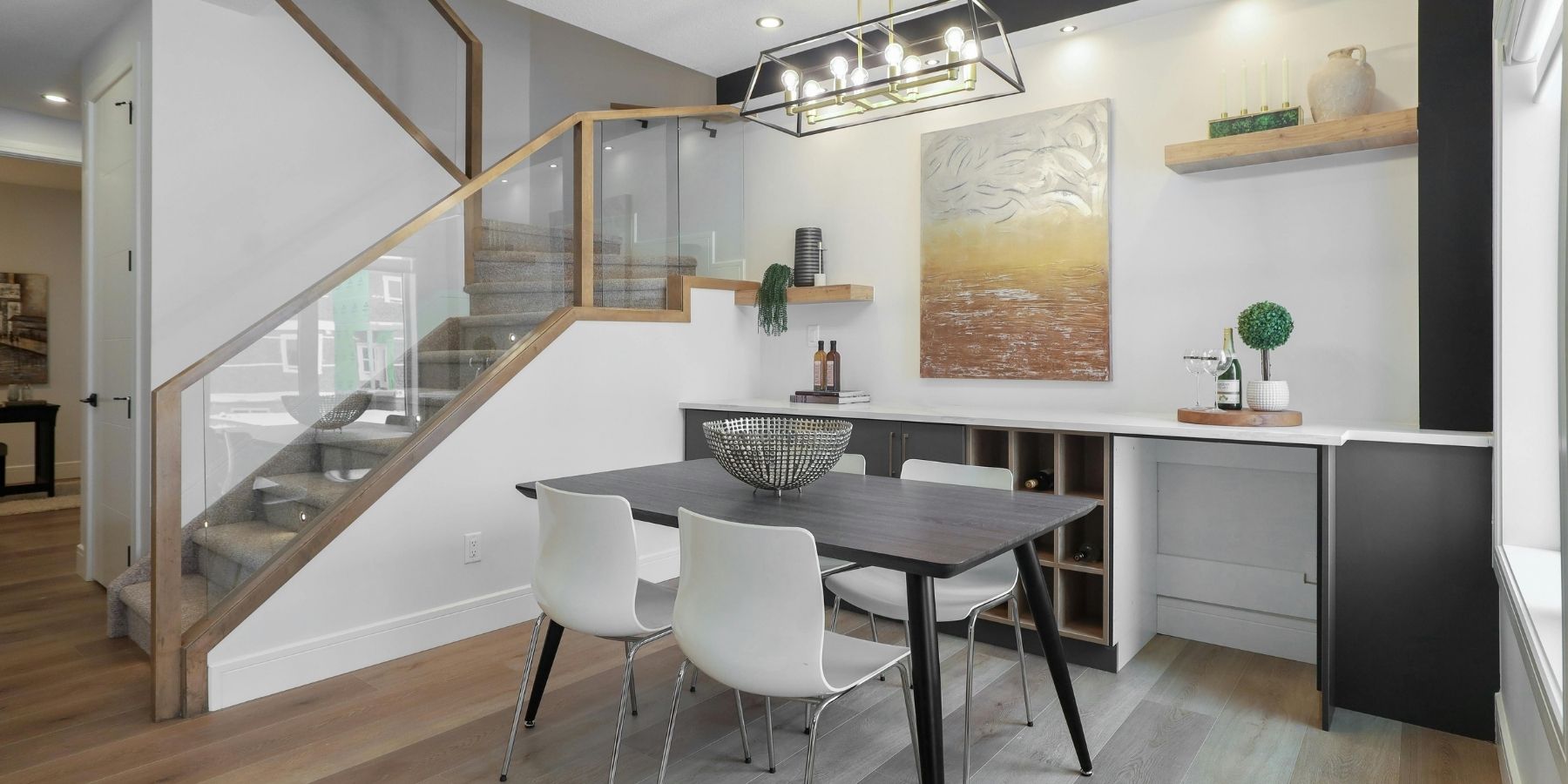 Modern dining area with glass-balustrade staircase, built-in storage and contemporary lighting