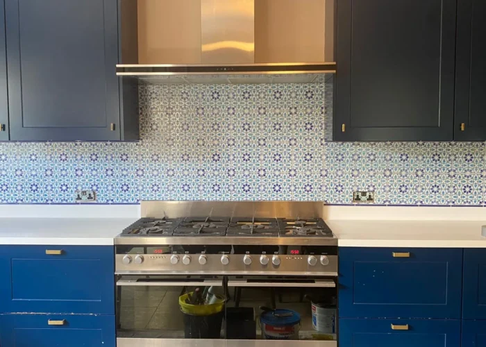 Finished kitchen with blue cabinetry, range cooker and patterned tiled splashback