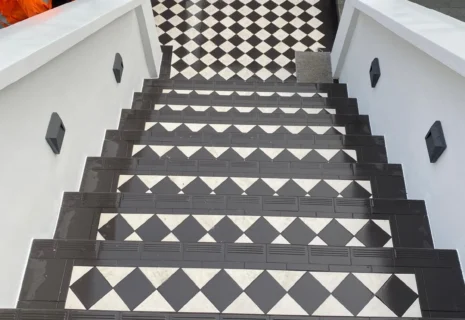 Restored exterior entrance steps with black and white geometric tiles and rendered side walls
