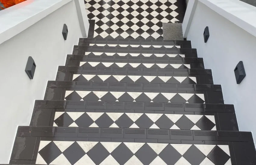 Restored exterior entrance steps with black and white geometric tiles and rendered side walls