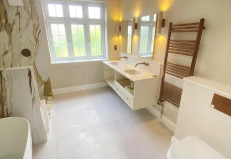 Luxury bathroom with double vanity, wall-hung toilet, heated towel rail and marble-effect wall finishes