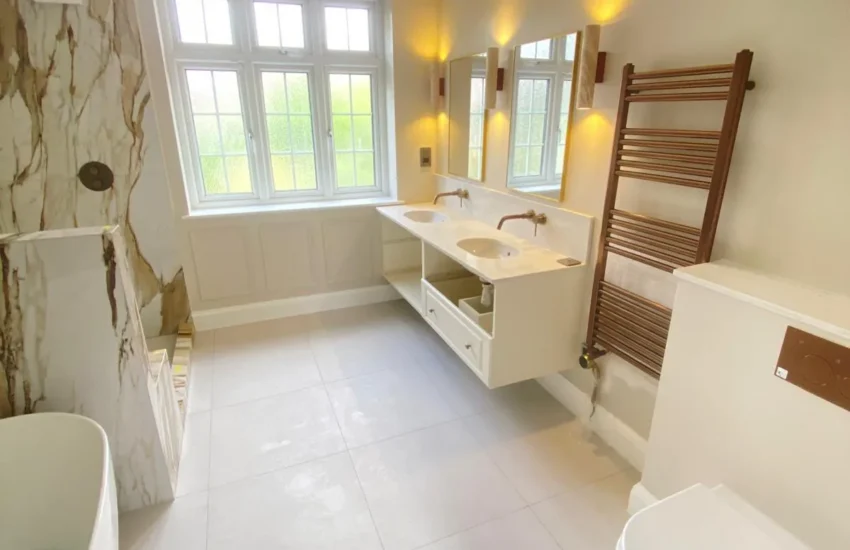 Luxury bathroom with double vanity, wall-hung toilet, heated towel rail and marble-effect wall finishes
