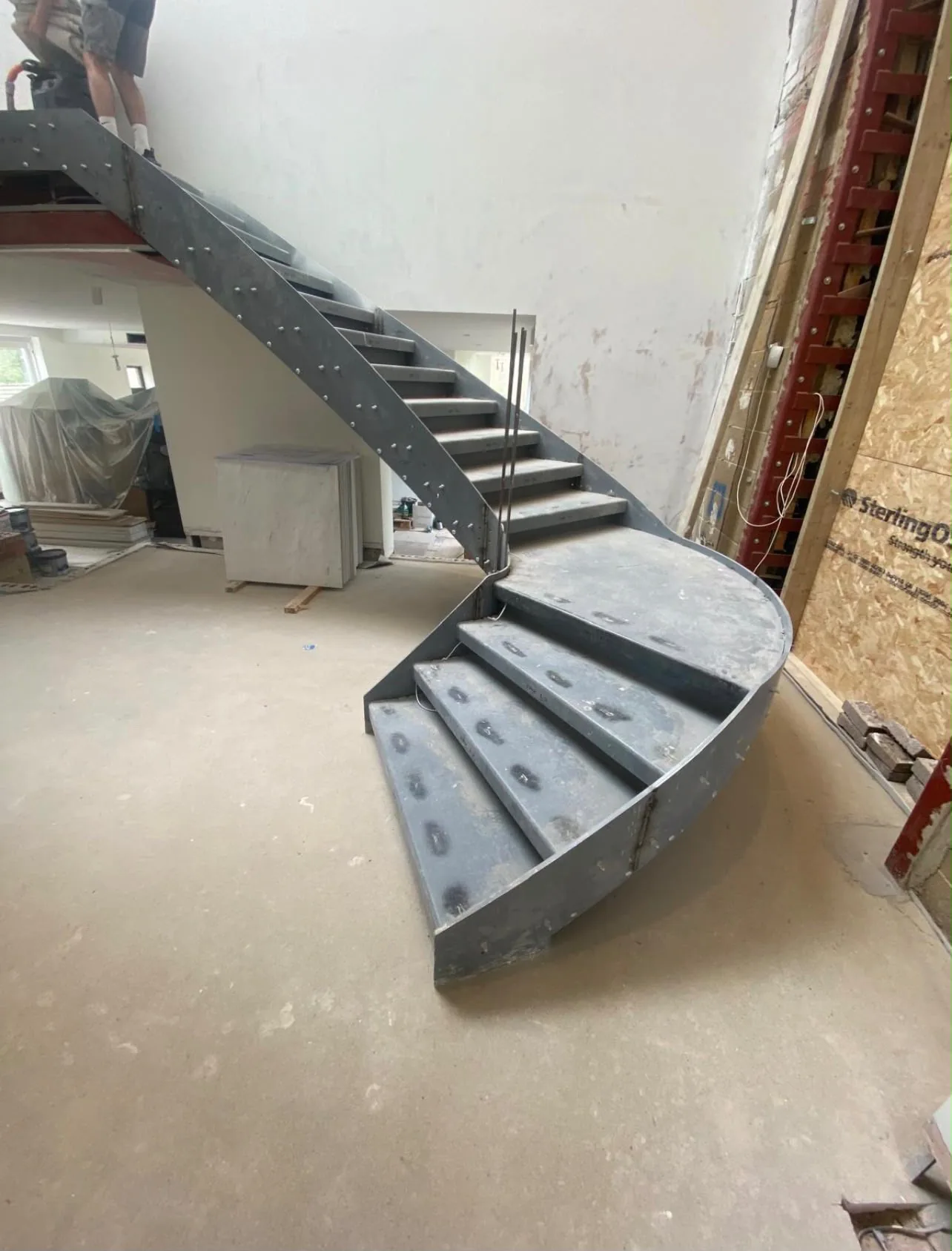 Bespoke curved steel staircase being installed during a residential renovation