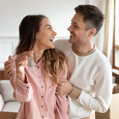 Smiling couple holding keys together inside a residential property