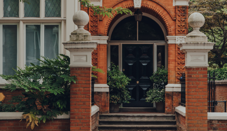 Ornate brick entrance with black front door and stone detailing on a period property in Kensington, London