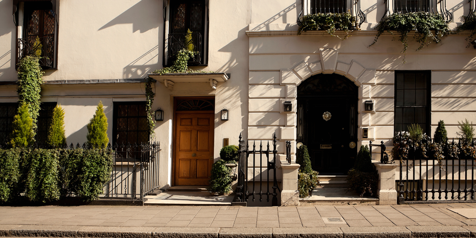 Elegant period townhouse entrances with traditional doors, iron railings and planted front gardens