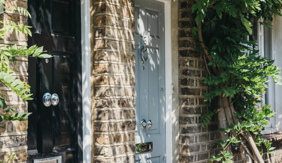 Traditional brick townhouse entrances with painted front doors and climbing greenery