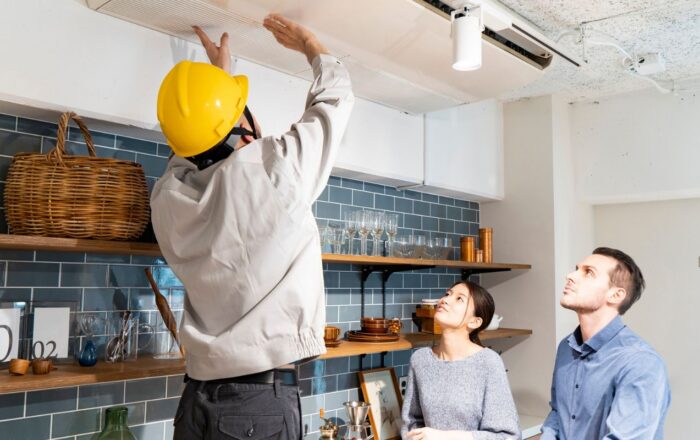 Property maintenance professional inspecting a ceiling while speaking with residents