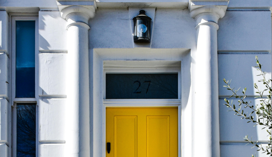 Period townhouse entrance with white stucco facade and yellow front door in Notting Hill, London