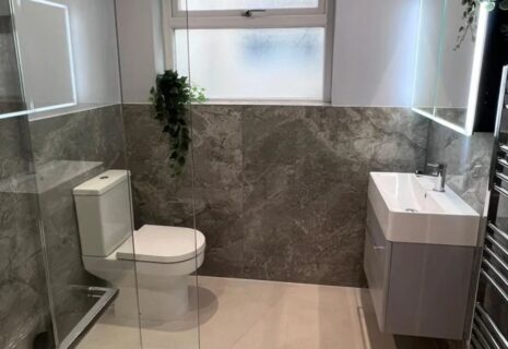 Modern compact bathroom with walk-in shower, tiled walls, vanity unit and heated towel rail