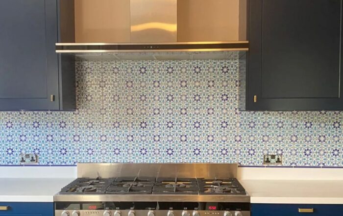 Patterned tile splashback installed behind a kitchen hob and worktop