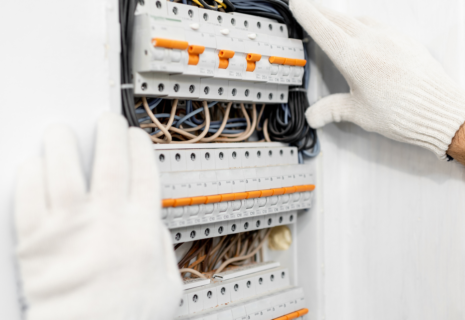 Electrician inspecting a consumer unit with circuit breakers and electrical wiring