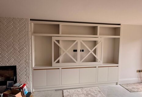 Bespoke built-in media unit with shelving and fitted cabinets beside a fireplace