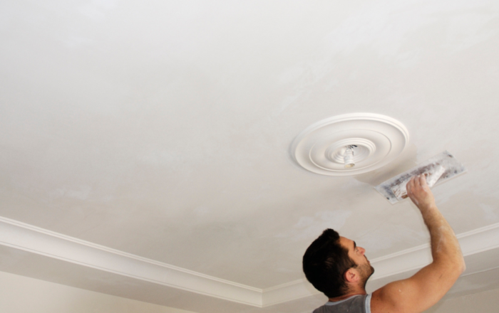 Tradesperson smoothing fresh plaster on an interior ceiling