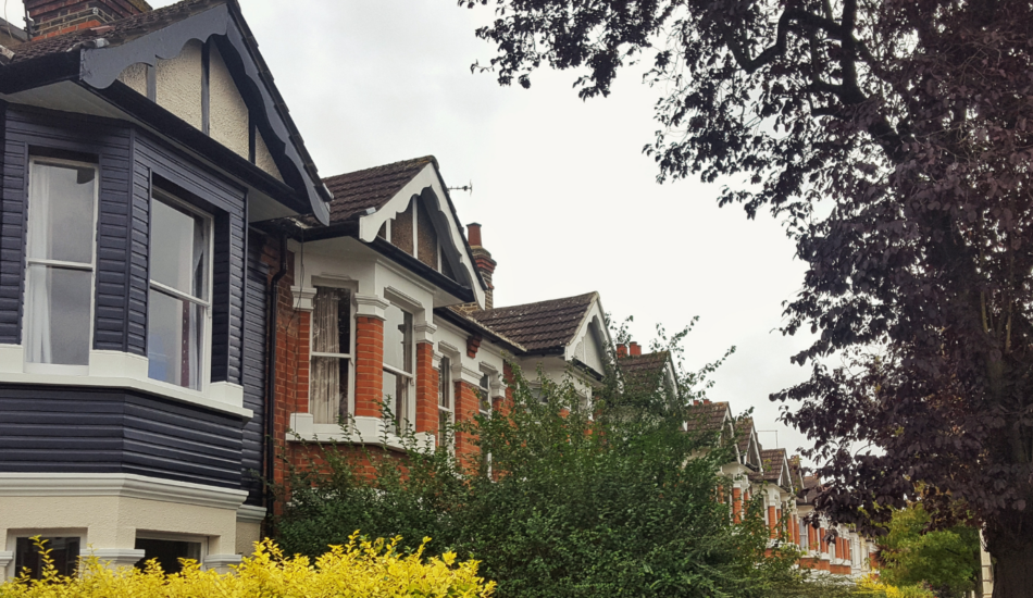 Row of period residential houses with bay windows, front gardens and mature trees in Ealing