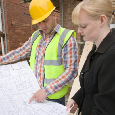 Construction professional and client reviewing building plans together on site
