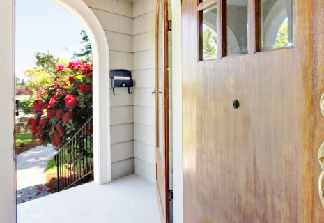 Residential front entrance with wooden door, covered porch and arched opening